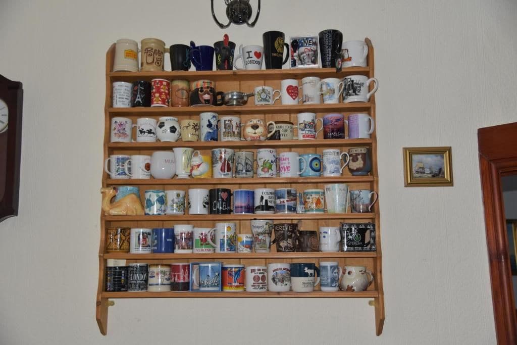 Estante de pared con una variedad de tazas y pequeños objetos decorativos.