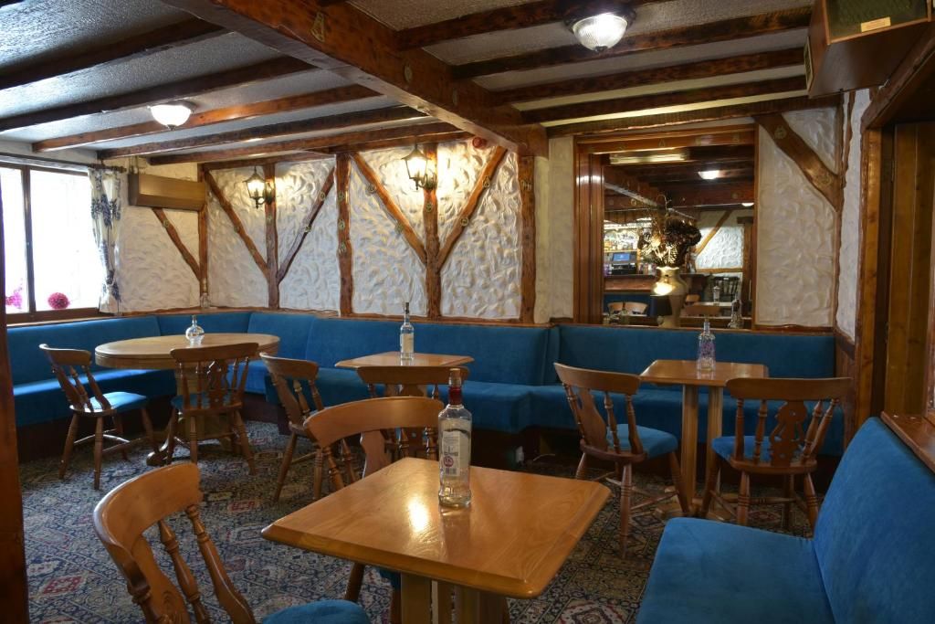 Un interior de restaurante con vigas de madera, asientos tapizados en azul y mesas redondas.