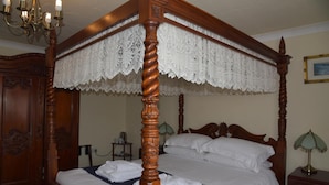 A four-poster bed with a lace canopy, wooden headboard, and a bedside table with a lamp. - Dinorben Arms Hotel (Amlwch)