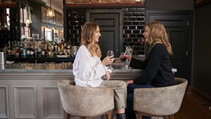 Dos personas sentadas en una barra con una variedad de botellas y copas.