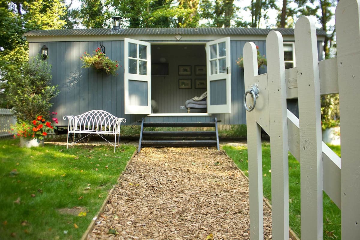 A small, single-story building with a porch, a bench, and a pathway leading to the entrance.