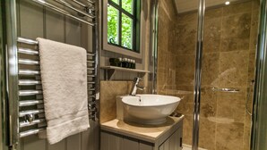 Un baño moderno con lavamanos independiente, cabina de ducha con mampara de vidrio y un perchero para toallas.