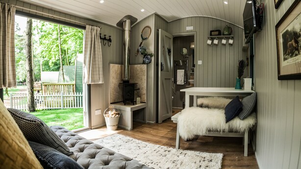 Una sala de estar acogedora con un sofá, un sillón blanco y mullido, una mesa de madera y una chimenea.