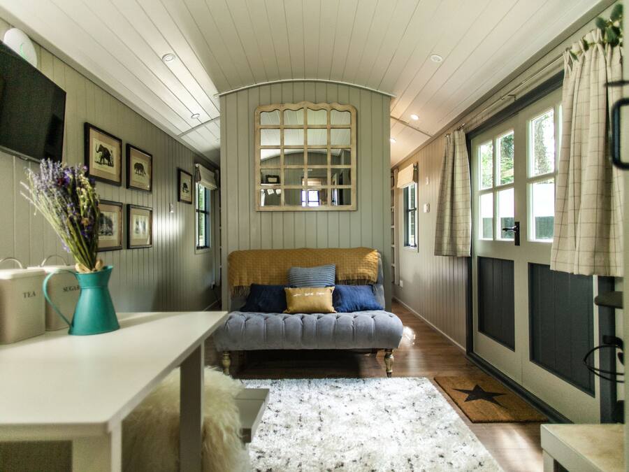 Una habitación acogedora con sofá, una mesa de centro y un jarrón de flores.