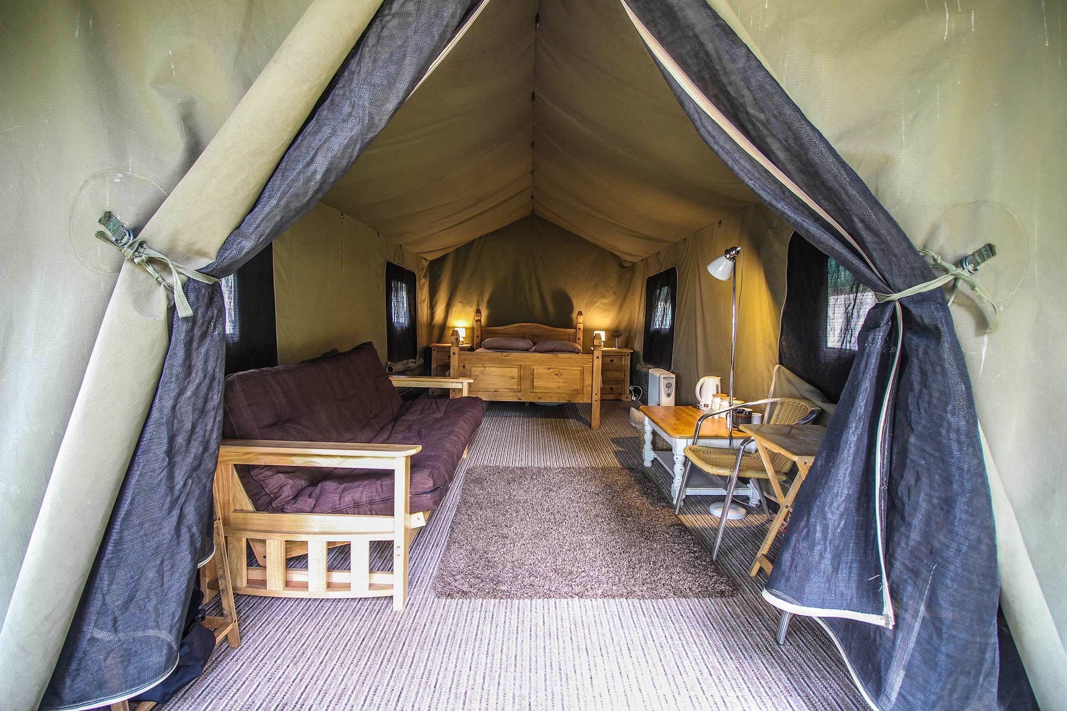 Ein Zelt mit Bett, einer Couch und einem Tisch mit Stühlen.