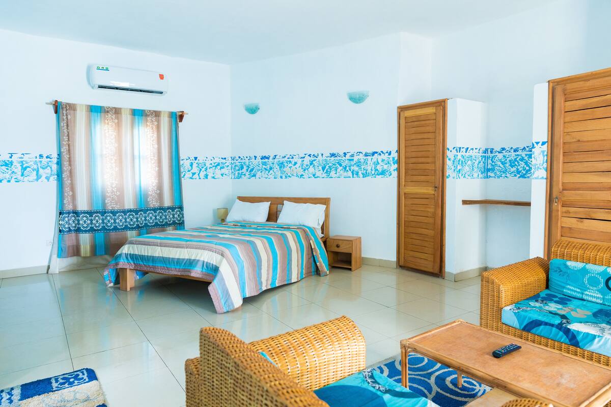 A room with a bed, a sofa, a small table, and a wardrobe.