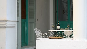 A white balcony with a table and chairs, a bottle of wine, and a glass of wine. - Neoclassical ART-House Bhive (Athens)