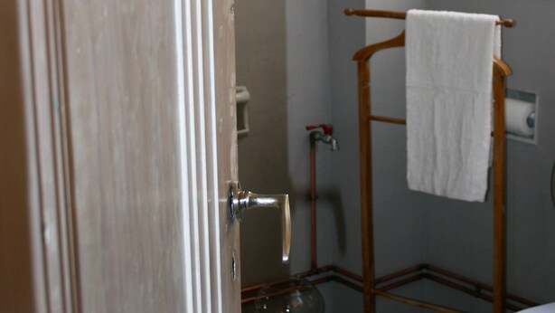 A bathroom with a toilet, a towel rack, a glass bowl, and a shower area. - Neoclassical ART-House Bhive (Athens)