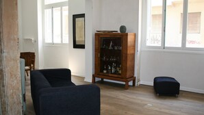A room with a dark blue sofa, a wooden cabinet with glass doors, and a small ottoman. - Neoclassical ART-House Bhive (Athens)