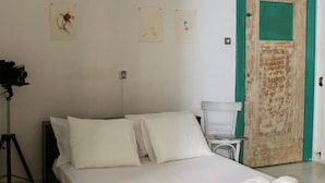 A bedroom with a single bed, white bedding, a wooden headboard, a green-framed door, and a tripod with a camera on a tripod. - Neoclassical ART-House Bhive (Athens)