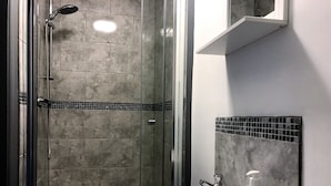 A bathroom with a glass-enclosed shower, a white sink, and a mirror above it. - No57 (Crewe)