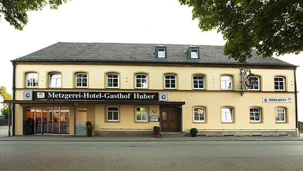 Un edificio de dos pisos con un letrero que dice 'Metzgerei-Hotel-Gasthof Huber'.