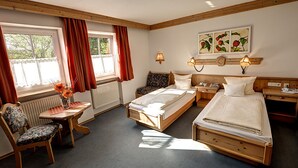 Una habitación de hotel con dos camas, un escritorio, una silla, un radiador y una ventana con cortinas.