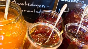 Variedad de bebidas, incluyendo un vaso grande con pajita, y varios frascos de mermelada con cucharas.