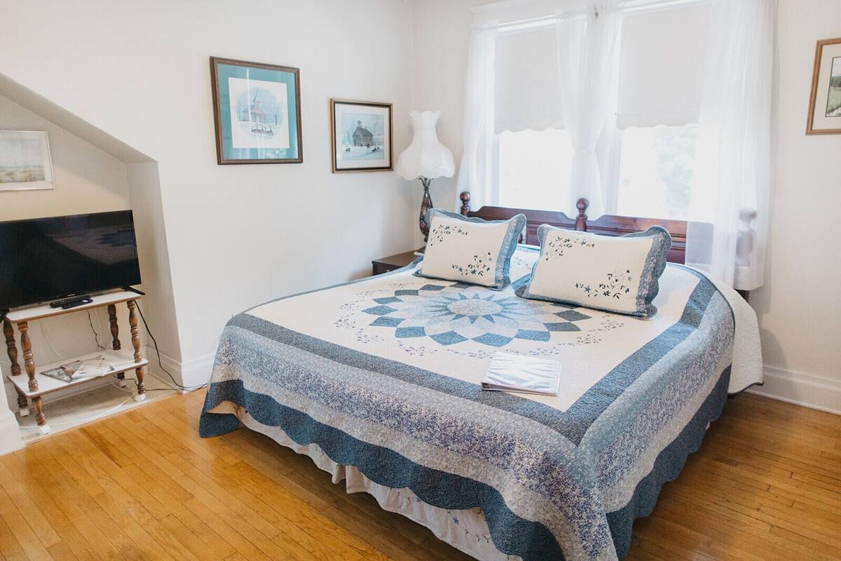 A bedroom with a bed, a television on a stand, and framed pictures on the wall.
