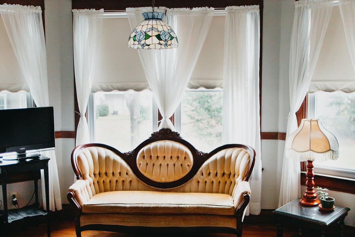 A room with a sofa, a television, a lamp, and a window with curtains.