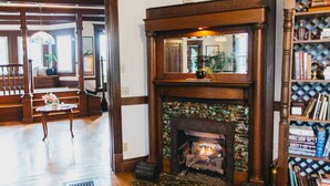 A room with a fireplace, wooden bookshelves, and a staircase leading to another area. - Friendly City Inn Bed & Breakfast (Harrisonburg)