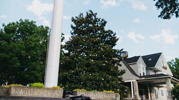 A flagpole with an American flag, a stone sign for Friendly City Inn, and a house in the background.