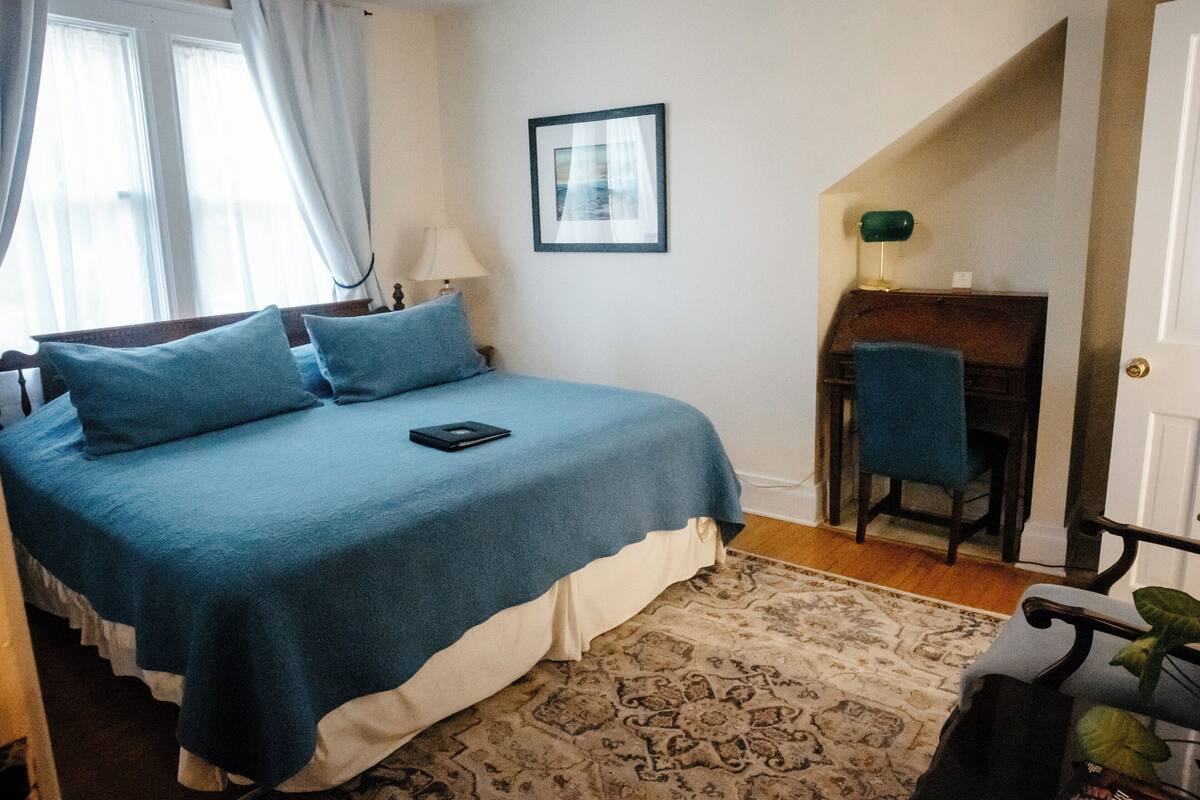 A bedroom with a bed, a desk, and a chair.