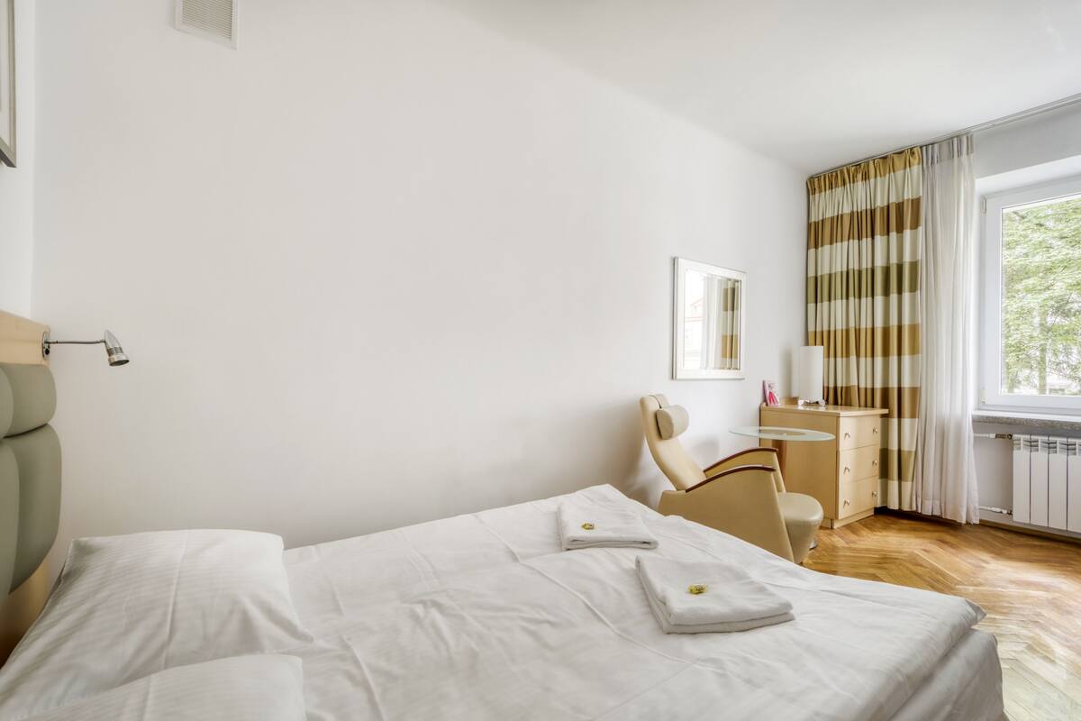 Ein Hotelzimmer mit Bett, Schreibtisch, Stuhl und einem Vorhangfenster.