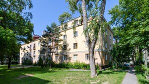 Ein mehrstöckiges Gebäude mit Balkonen, umgeben von Bäumen und Grün.