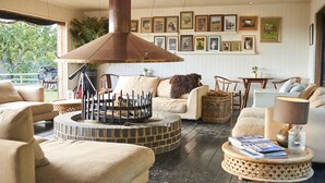 A cozy living room with a fireplace, comfortable seating, and framed pictures on the wall. - Treehouse Hotel - At Port Lympne Reserve (Hythe)