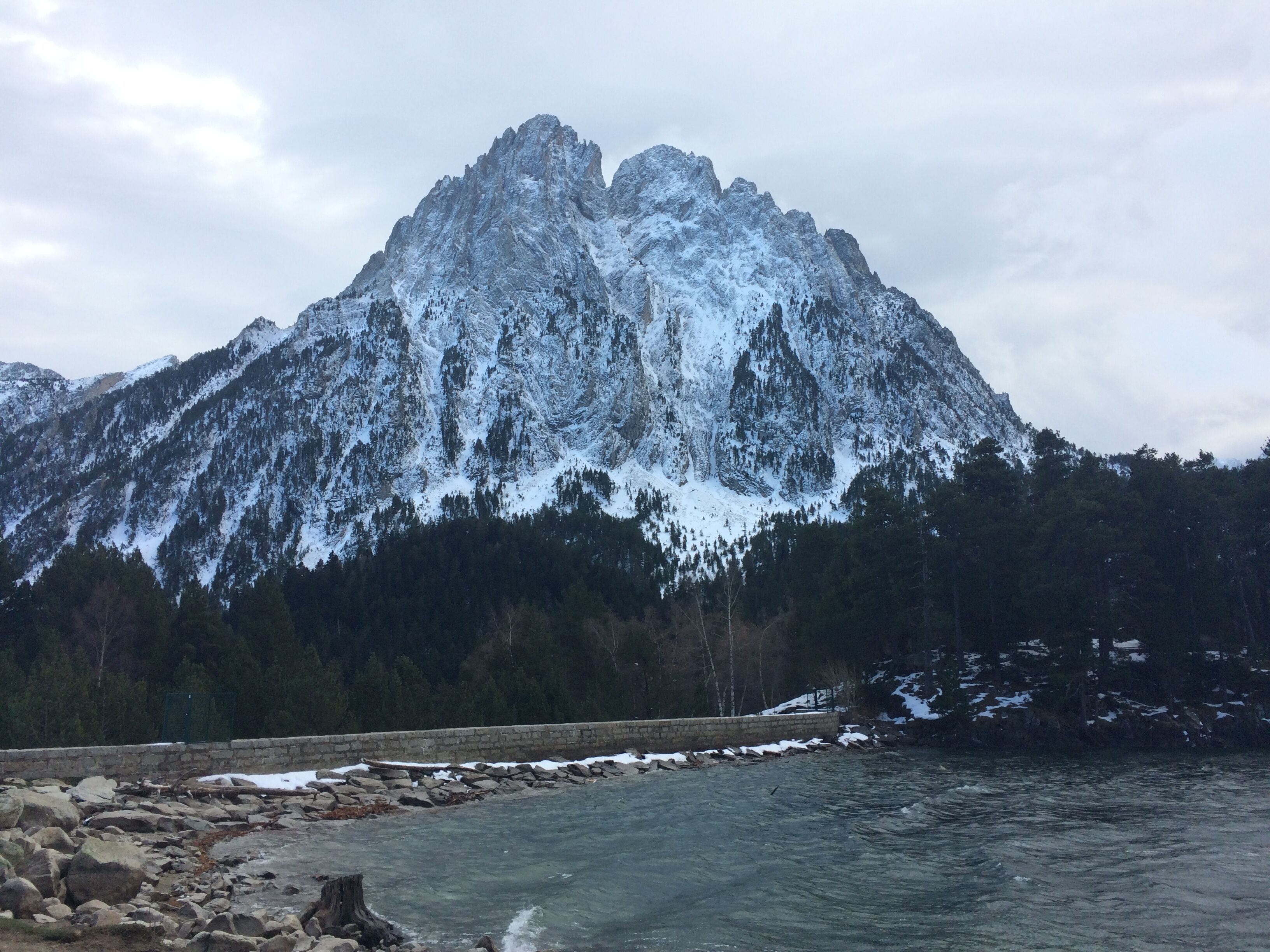 Une montagne aux sommets enneigés, avec une rivière au premier plan.