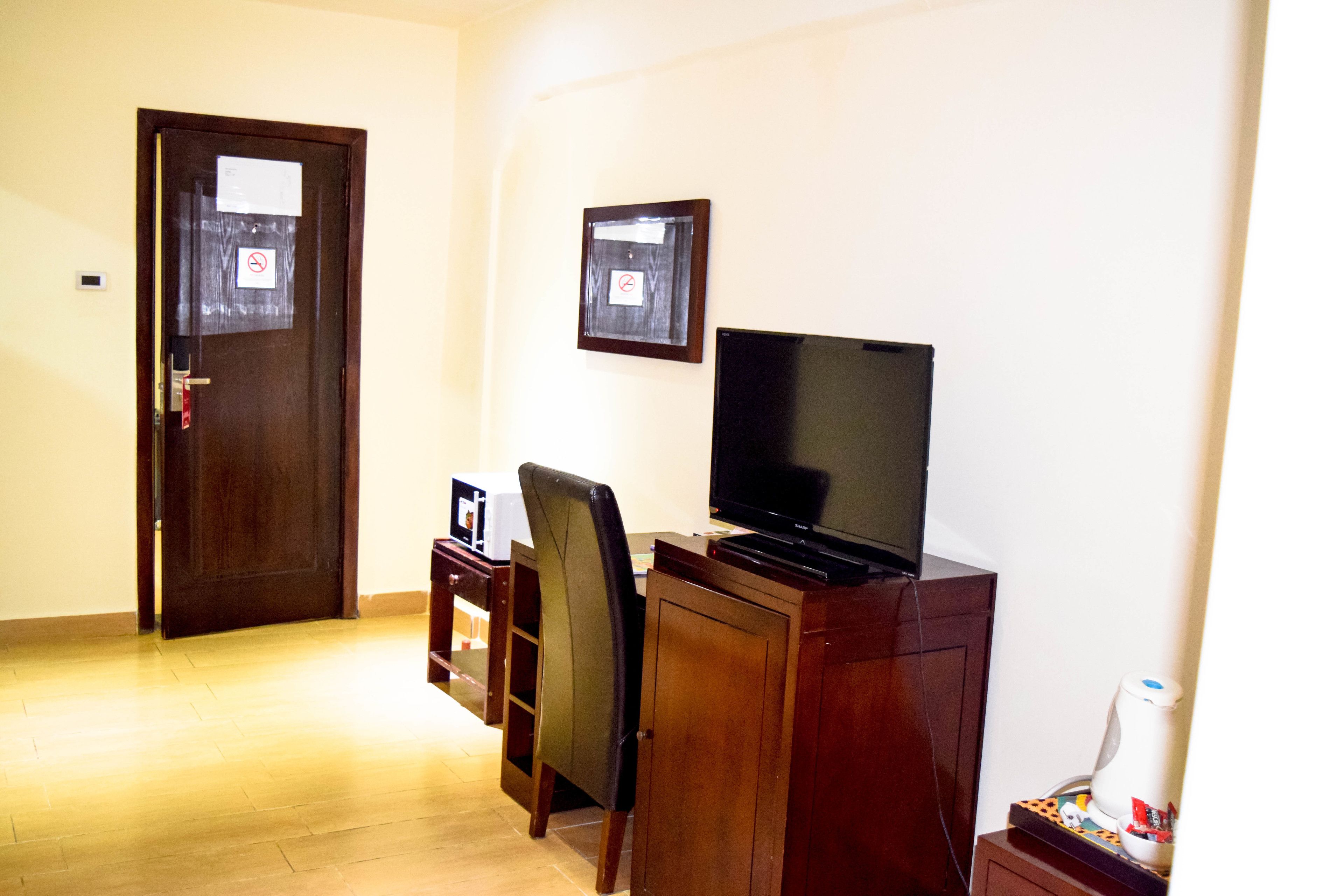 Ein Zimmer mit einem Holztisch, einem Fernseher, einem Stuhl und einer Tür.