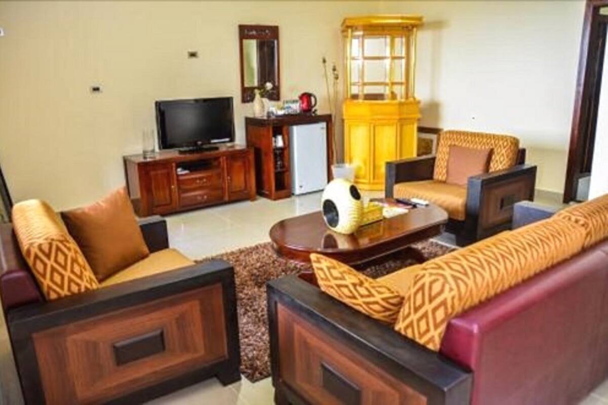 A living room with a sofa set, a television, a cabinet, and a decorative lamp.