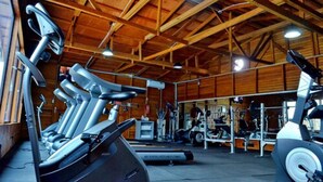 A gym with exercise equipment, wooden beams, and a ceiling fan. - The Cape Hotel (Monrovia)