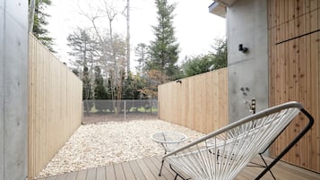 A wooden deck with a white wire chair and a small round table.