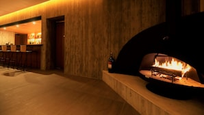 A modern interior with a wood-paneled wall, a bar area with stools, and a fireplace. - Regina Resort Kyukaruizawa (Karuizawa)