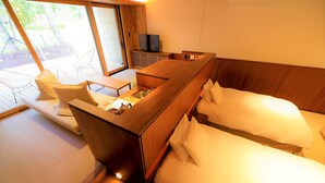 A hotel room with a wooden desk, a bed with white linens, and a seating area with chairs and a table. - Regina Resort Kyukaruizawa (Karuizawa)