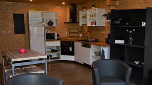 A kitchen with white cabinets, a microwave, a sink, and a dining area with two chairs and a table. - Le Toit de Dinant - Esc’Appart (Dinant)