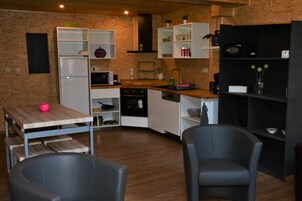 Una cocina con armarios blancos, microondas, lavamanos y comedor con dos sillas y una mesa.