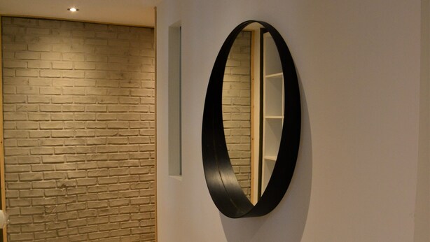 A hallway with a wooden floor, a brick wall, and a round mirror on the wall. - Le Toit de Dinant - Esc’Appart (Dinant)