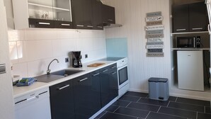 A modern kitchen with dark cabinets, a white countertop, a coffee maker, a microwave, and a refrigerator. - Apartment / Monteurzimmer (Seesen)