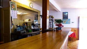 Een restaurantinterieur met een houten toonbank, een espressoapparaat en potplanten.