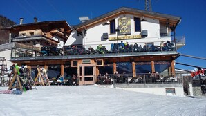 Ein Skigebäude mit einem Restaurant im Obergeschoss und einem Skiverleih im Erdgeschoss.