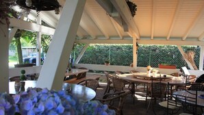 An outdoor patio with round tables and wicker chairs, surrounded by potted plants and a white fence. - Hotel Krone Kappel (Kappel-Grafenhausen)