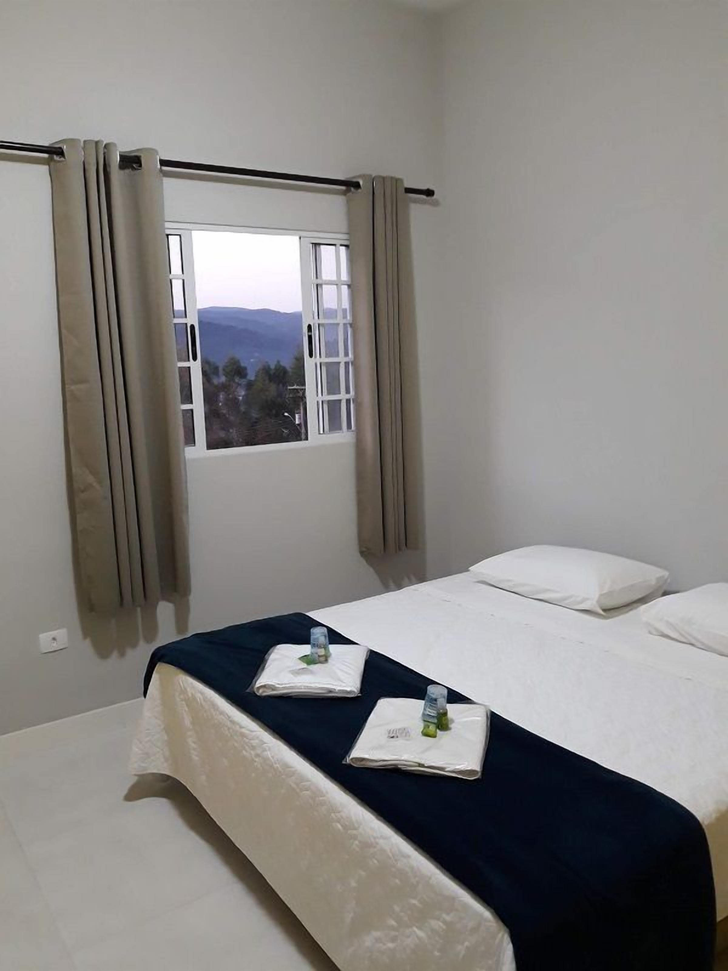 Une chambre d’hôtel avec un lit, une fenêtre avec des rideaux et une vue sur l’extérieur.