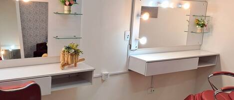 A salon with two mirrors, a vanity, and red chairs.