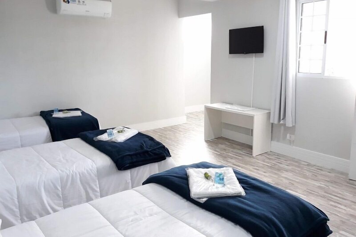 Habitación de hotel con dos camas, un escritorio, un televisor y una ventana con cortinas.