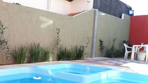 A rectangular swimming pool with clear blue water, surrounded by a tiled patio area. - Pousada Top (Mairipora)