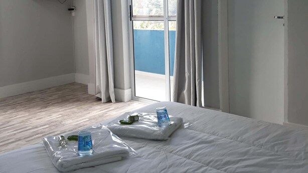 A hotel room with a bed, a television on the wall, a sliding glass door, and a view of the outside. - Pousada Top (Mairipora)