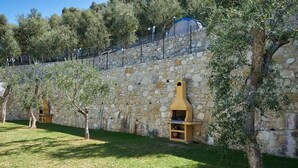 A stone wall with two outdoor ovens and a grassy area with trees. - Agricampeggio Agri-camping Relax (Brenzone sul Garda)