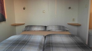 A double bed with a plaid bedspread, two bedside tables, and a wall-mounted light fixture. - Agricampeggio Agri-camping Relax (Brenzone sul Garda)