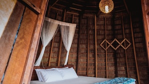 A wooden room with a bed, a hanging light fixture, and a woven wall decoration. - Sao Bien Cam Ranh (Nam Cam Ranh)