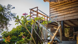 A wooden structure with a thatched roof, a staircase leading to a platform, and lush greenery around. - Sao Bien Cam Ranh (Nam Cam Ranh)