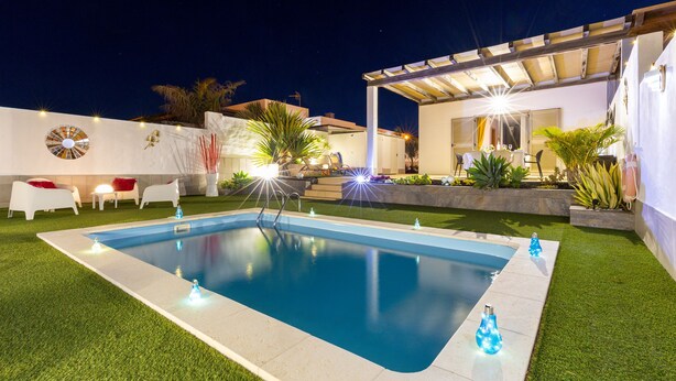 Une piscine dotée d’une pergola et d’un espace salon extérieur.